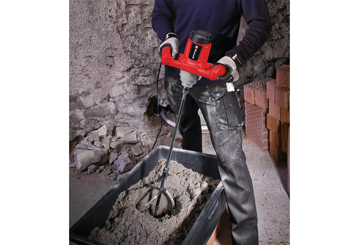 Απεικονίζεται άνδρας να χρησιμοποιεί τον αναδευτήρα για να ανακατέψει δομικά υλικά μέσδα σε ένα δοχείο.